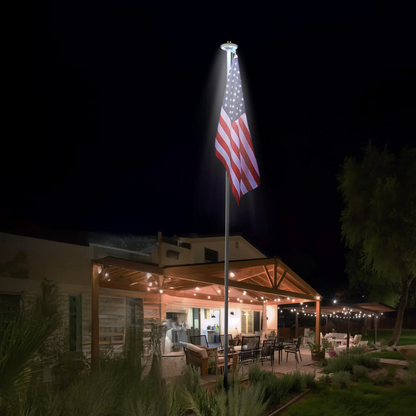Outdoor setting with a flagpole featuring an American flag at night.